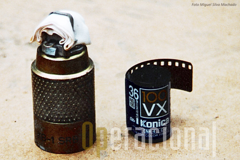 Um "cluster bomblet" KB 1 idêntica à que vitimou os portugueses e italianos em 1996. Aqui fotografada uma nova, junto a um rolo fotográfico para dar noção das dimensões.