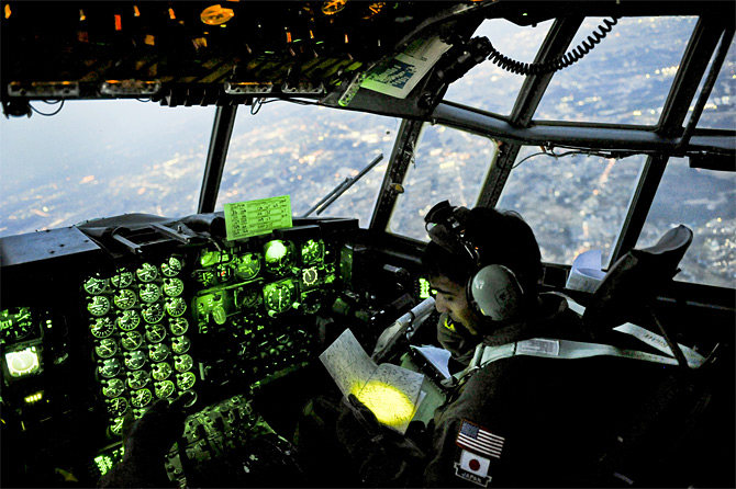 O capitão Yuri Batten da Força Aérea dos EUA aos comandos de um C-130 no decurso de uma missão de transporte de medicamentos em 19 de Março de 2011 (Foto US Air Foce pelo Staff Sgt. Jonathan Steffen).